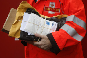 A Royal Mail Group Ltd. employee carries a bundle of letters during his delivery round in London, U.K. on Thursday, May 30, 2013. The U.K. government appointed UBS AG and Goldman Sachs Group Inc. as joint global coordinators and joint bookrunners for the sale of Royal Mail Group Ltd., the state-owned postal service. Photographer: Simon Dawson/Bloomberg via Getty Images