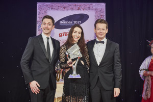 Rachel Hare on stage at The Henries last Thursday collecting the Best Christmas Box or Pack award for Paloma from (right) Nick Henry of sponsor Gould Paper and comedian John Robins who hosted the event.