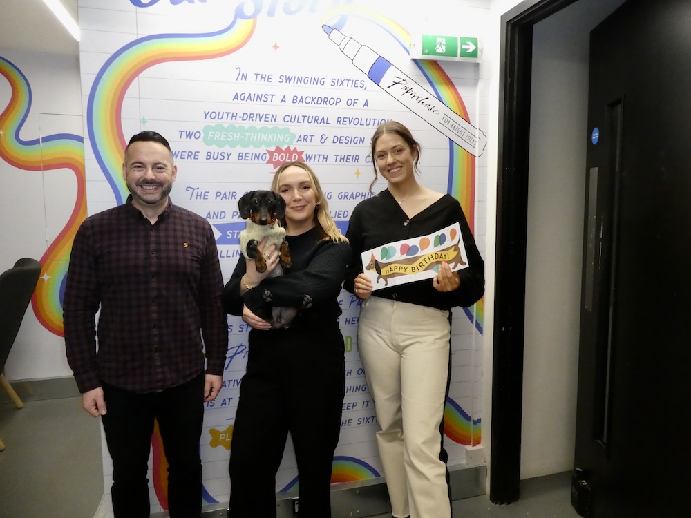 Above: Paperchase’s (left-right) Carlo Marinelli, Tori Heath-Smith (and her dog Elton…on ‘bring your dog to work day’) and Laura Clarke, holding the retailer’s best-selling everyday card, a Dachshund design, in the new HQ offices in Clerkenwell, London.
