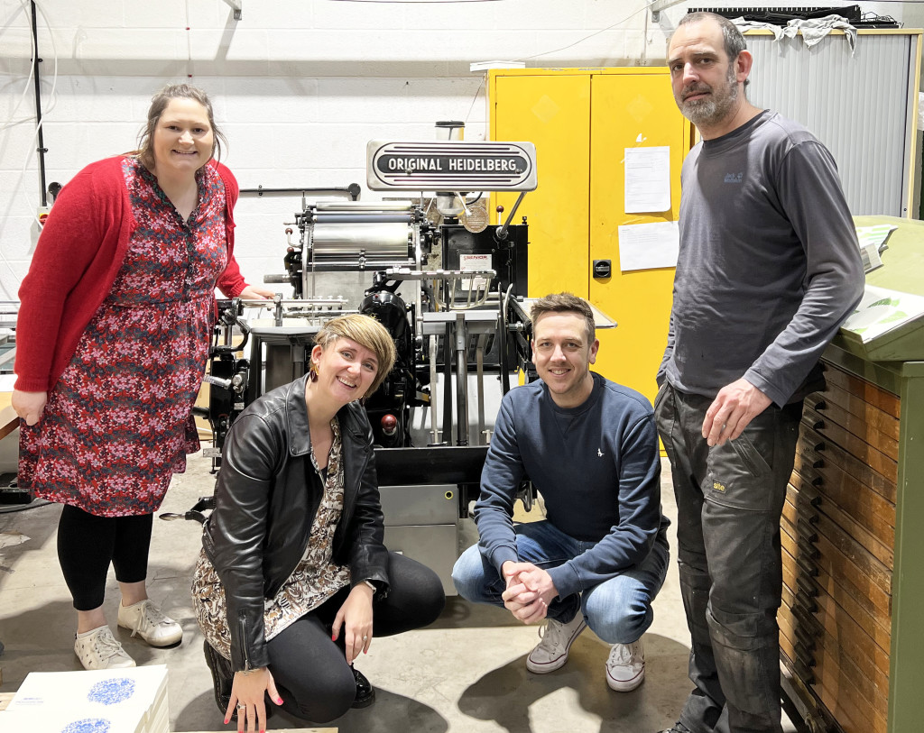 Above: Penguin Ink’s Lizzie Parker (second left) with Alpha’s Amy Muldrew, Luke Ostle (second right) and Richard Jones, and the Heidelberg platen press